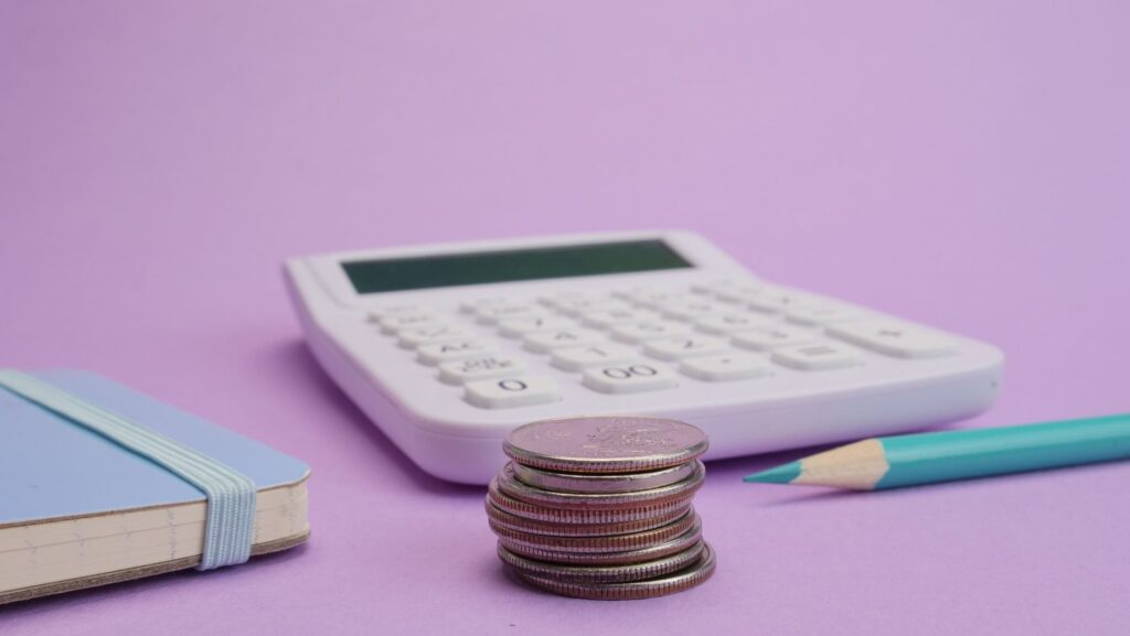 A calculator, coins, and a budget notebook