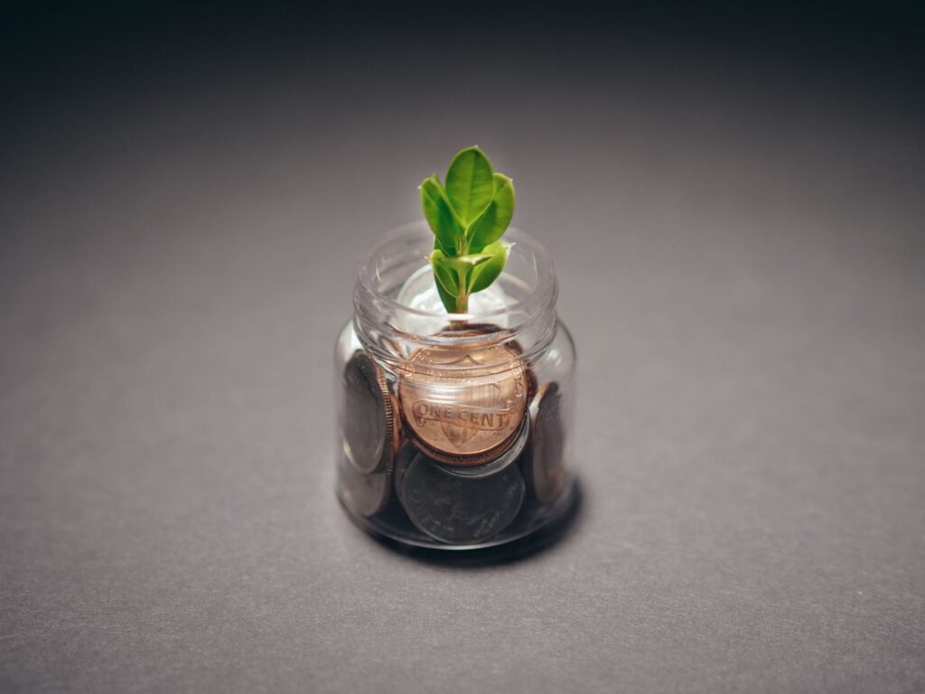 A jar of coins with a small plant, symbolizing savings growth