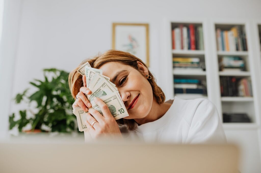 Happy woman with dollar bills, symbolizing financial success and fulfillment.