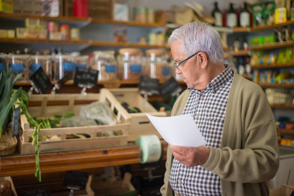 A grocery list beside fresh vegetables