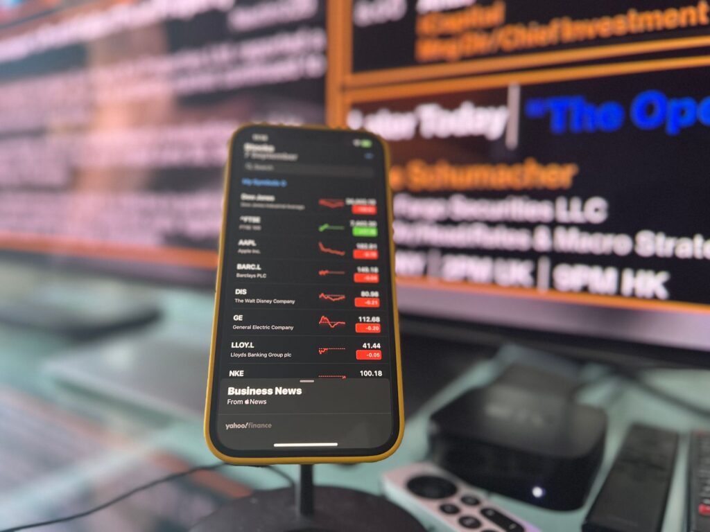 Person using a smartphone investment app with financial data on screen