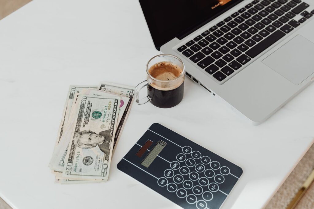 A budget planner, laptop and coffee on a clean desk