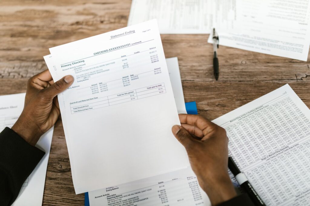 A person reviewing multiple payment obligations on a laptop spreadsheet