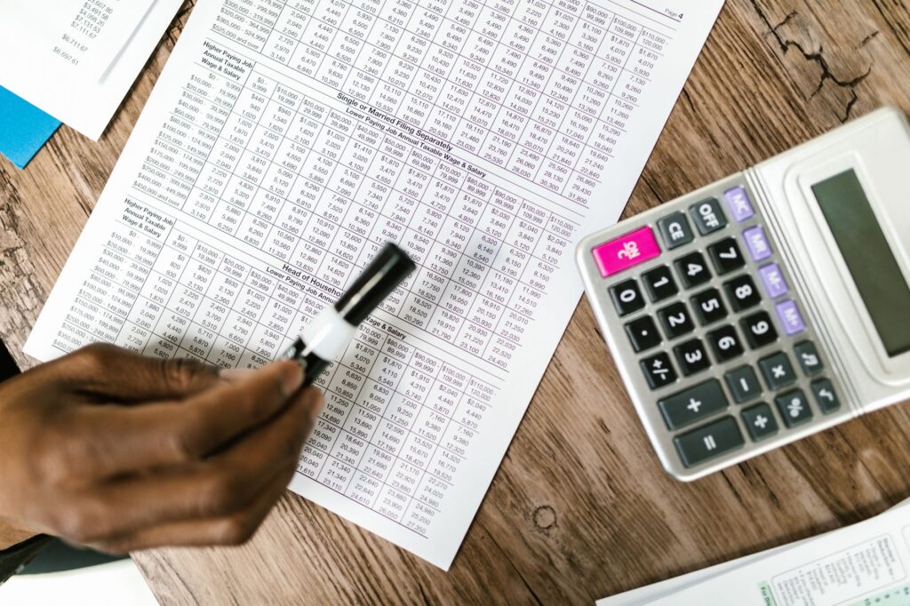 Person reviewing a monthly budget and calculator at a desk