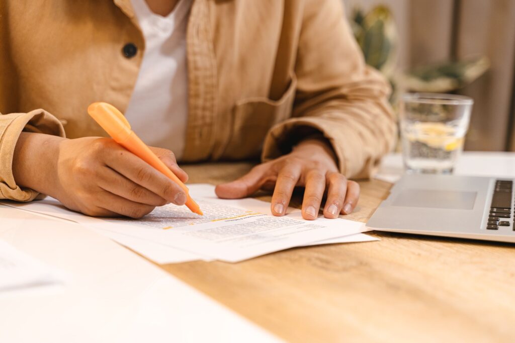 close-up of a hand reviewing and highlighting a printed document