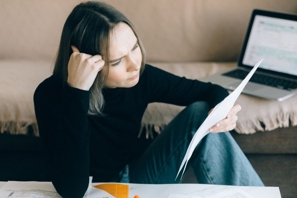 person calmly reviewing their finances on a laptop at a kitchen table