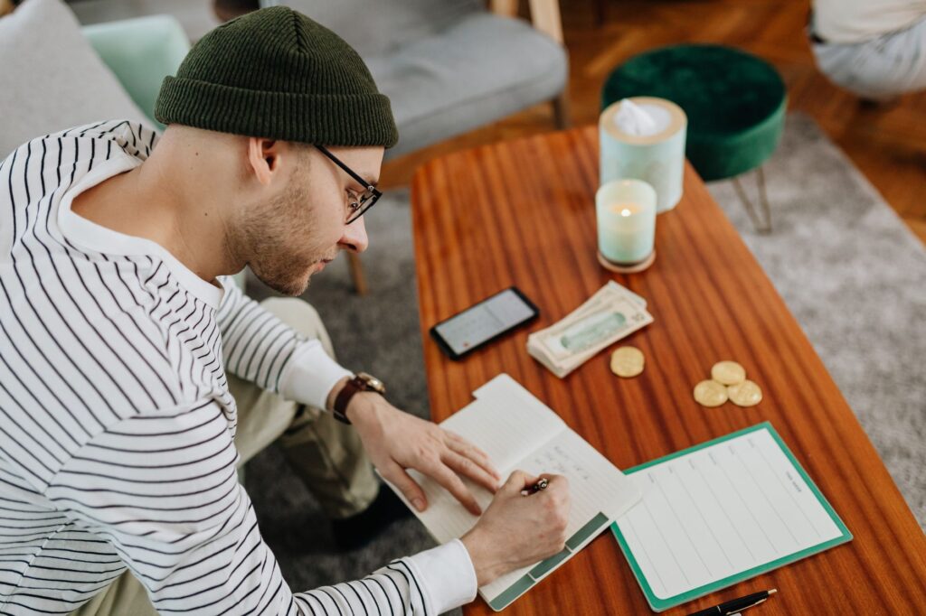 person writing out a staged financial recovery plan in a notebook