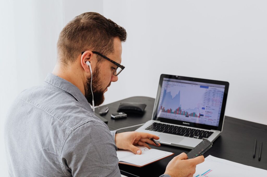 Person reviewing stock research on a laptop and phone